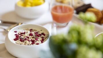 A breakfast setting with a bowl of cereal, a glass of juice, and a plate of food.