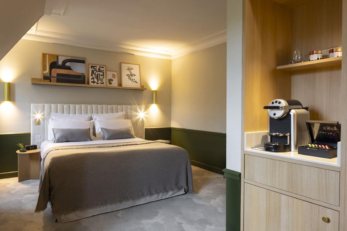 Een keurig opgemaakt slaapkamer met een groot bed, nachtkastjes, wandplanken en een klein kastje.