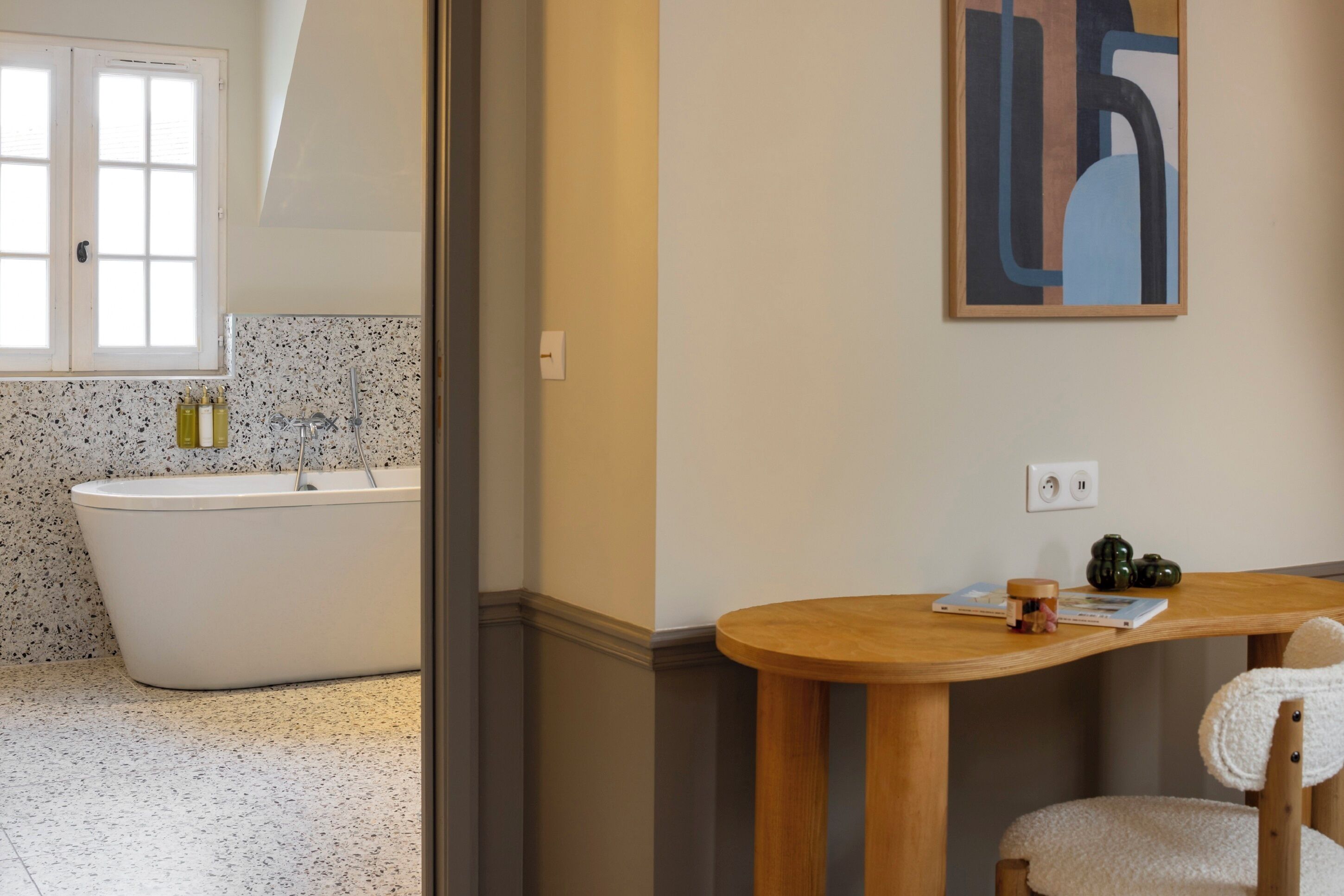Een badkamer met een vrijstaand bad, een houten wastafelmeubel en een handdoekrek.