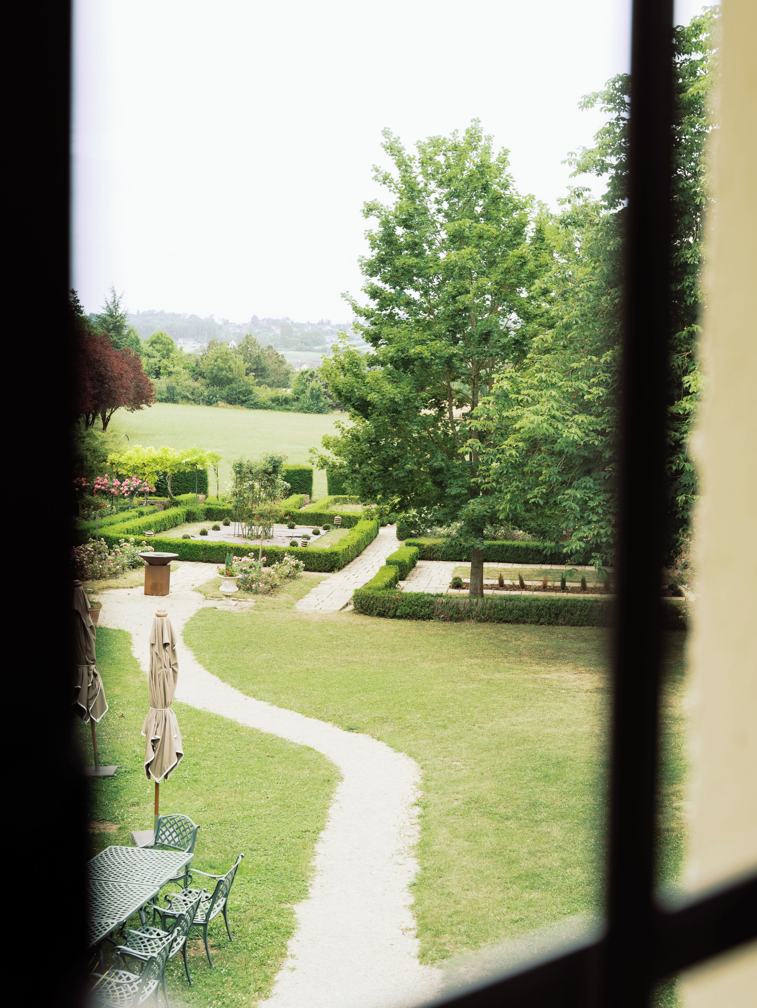 A garden view with a pathway leading to outdoor seating.