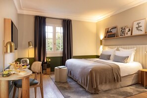 A hotel room with a bed, bedside table, lamp, chair, and a window with curtains.