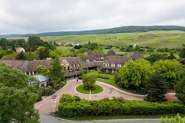 A large estate with multiple buildings, a central circular driveway, and surrounding lush greenery.