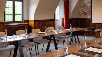 A conference room with a long table, chairs, water bottles, and a projector.