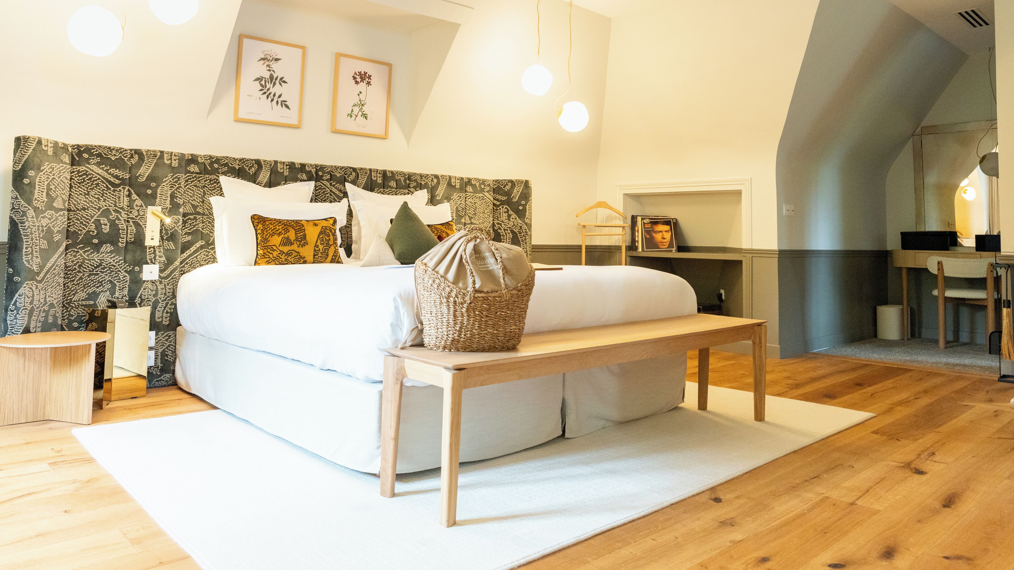 A modern bedroom with a large bed, bedside tables, a bench, and a headboard with a patterned design.