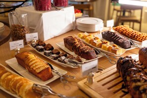 A buffet table with various baked goods and desserts.