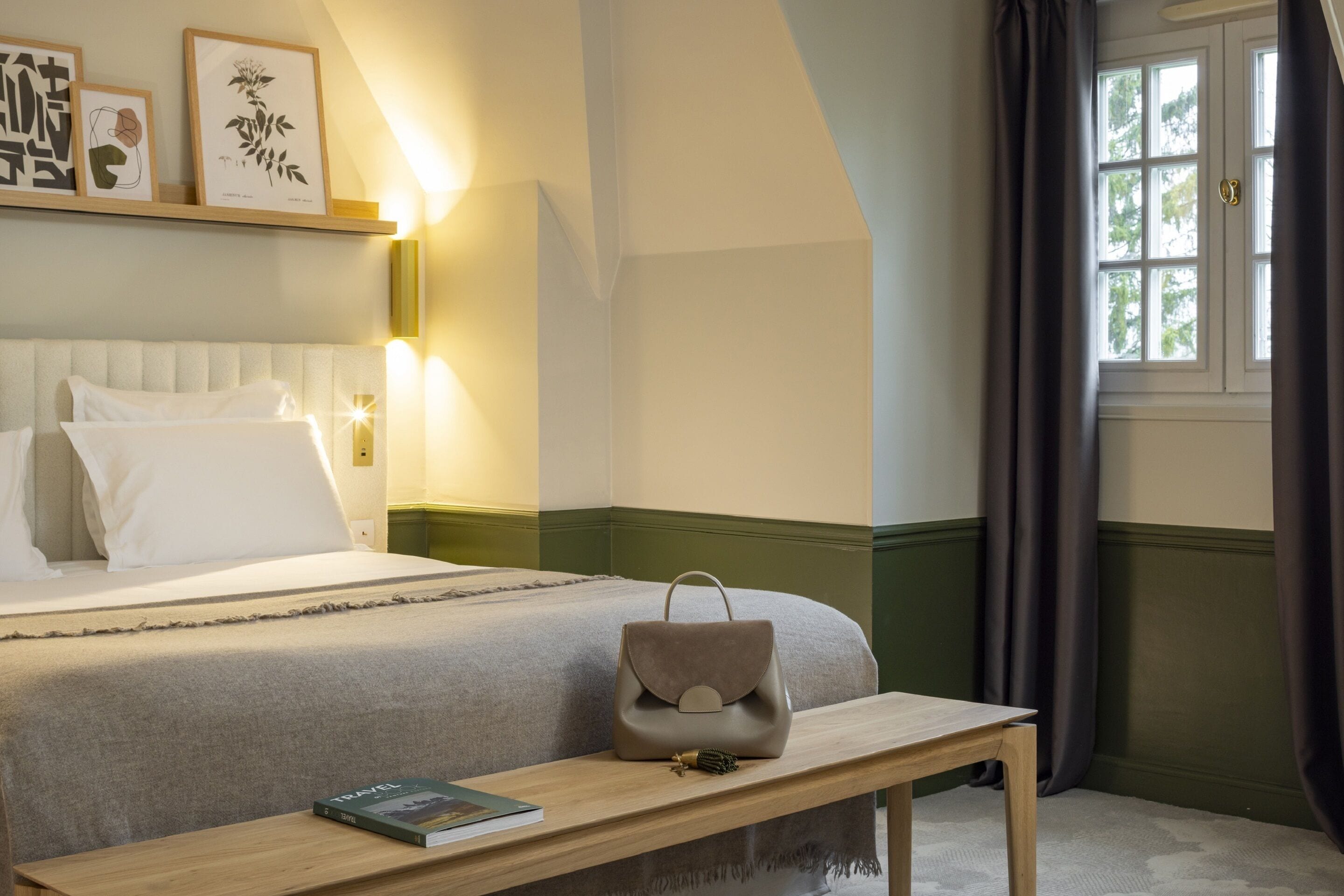 A neatly arranged hotel room with a bed, bedside table, and a window with curtains.