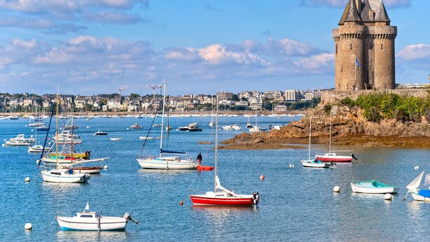 A coastal town with a prominent tower and numerous boats in the harbor. - La Malouinière Des Longchamps (Saint-Jouan-des-Guerets)