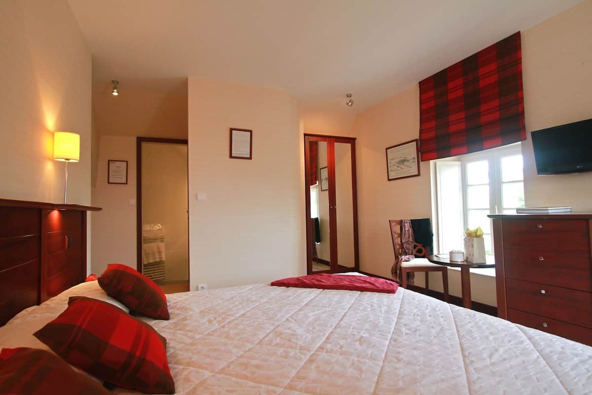 Ein Schlafzimmer mit Bett, Schminktisch, Stuhl, Spiegel und Fernseher.