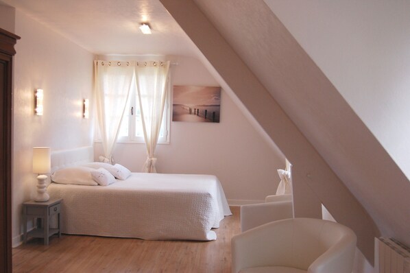A bedroom with a bed, a nightstand, a chair, and a picture on the wall.
