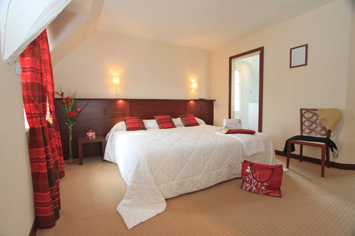 Ein Hotelzimmer mit einem großen Bett, einem Nachttisch, einem Sessel und einem Spiegel.
