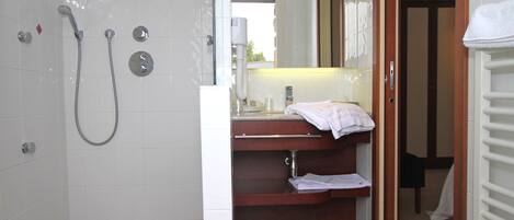Une salle de bain avec une douche, un lavabo avec un miroir et un porte-serviettes.