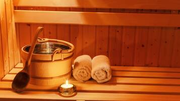 A wooden sauna bench with a wooden ladle, a metal container, and two rolled towels.