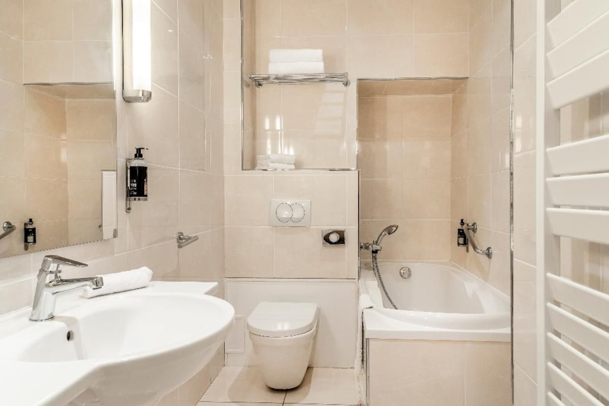 A modern bathroom with a sink, toilet, and bathtub.