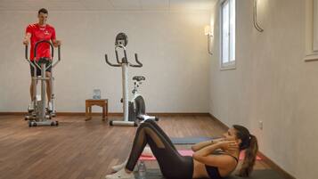 A gym with exercise equipment, a wooden floor, and a window.
