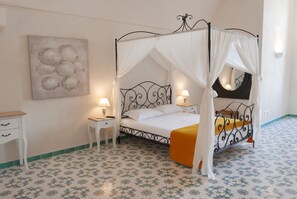 A bedroom with a four-poster bed, a bedside table, a nightstand, and a wall-mounted lamp.