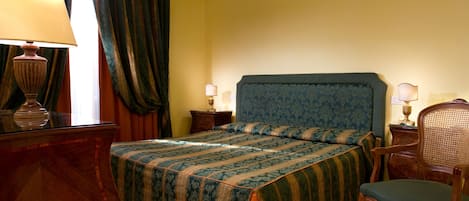 Un dormitorio con cama, dos mesitas de noche, una silla, una lámpara y un aparador.