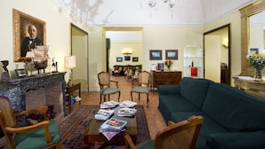 Amplia sala de estar con chimenea, un sofá verde y un comedor con sillas y una mesa.