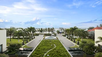 A landscaped courtyard with a central water feature, palm trees, and a view of a distant cityscape.