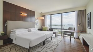 Een hotelkamer met een groot bed, een bureau en uitzicht op een wateroppervlak.