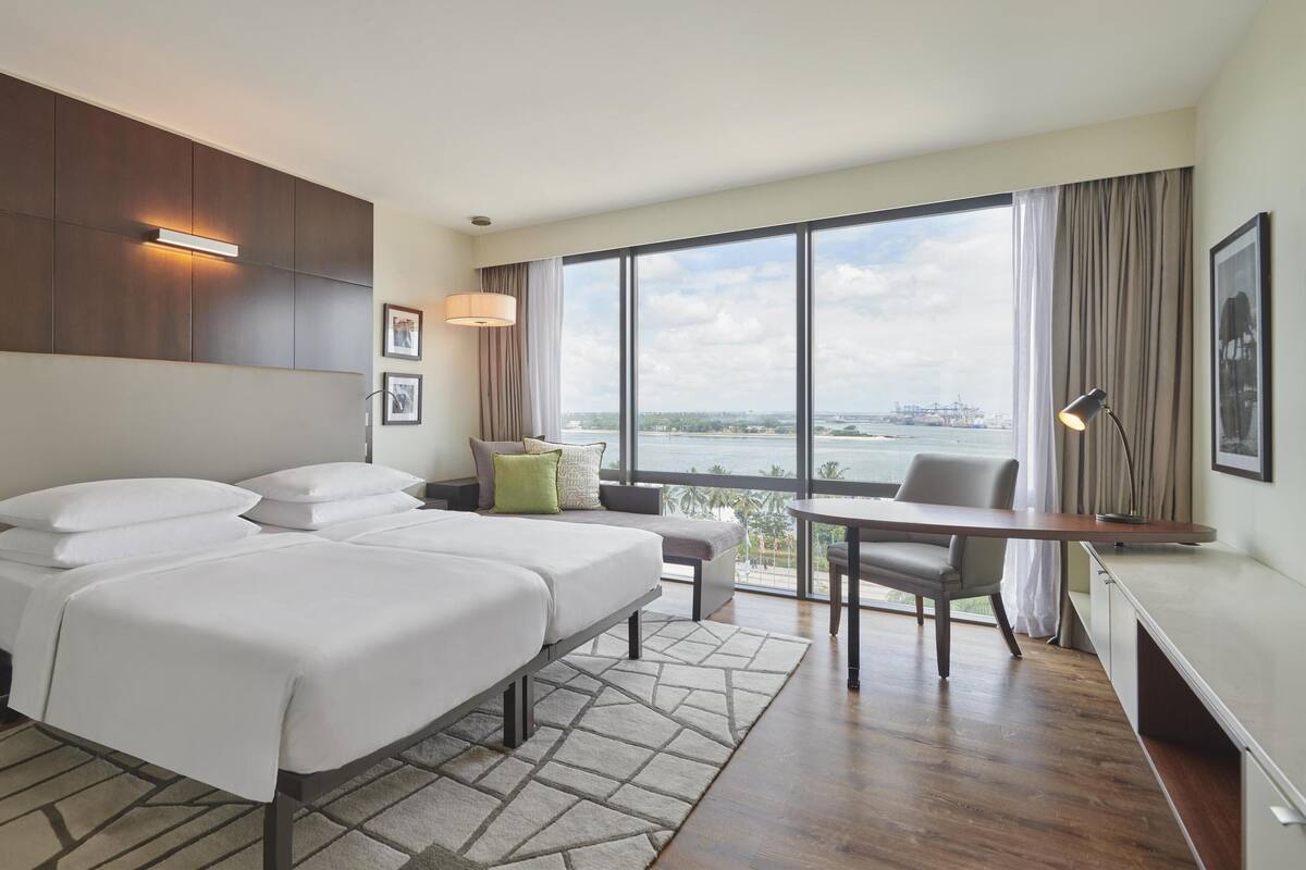 A hotel room with a large bed, a desk, and a view of a body of water.