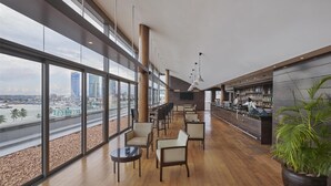 Een moderne bar met uitzicht op de skyline van de stad, houten vloeren en een grote potplant.