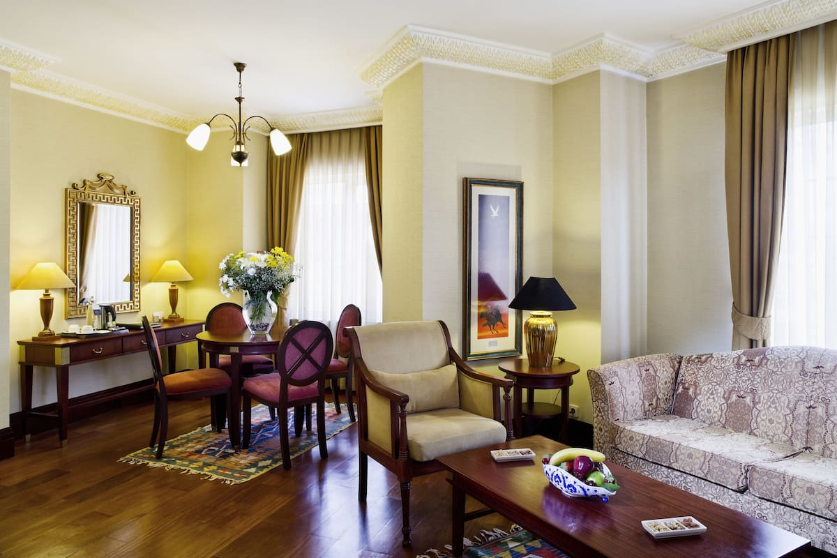 A well-furnished living room with a dining area, a sofa, a coffee table, and a painting on the wall.