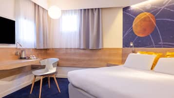 A hotel room with a bed, a desk, a chair, a TV, and a painting of a planet on the wall.