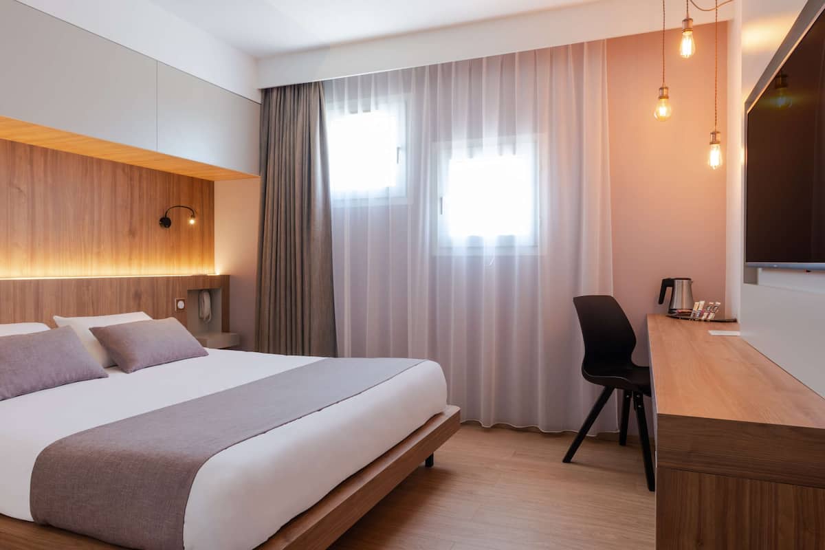 Ein modernes Hotelzimmer mit einem großen Bett, einem Schreibtisch und einem Stuhl.