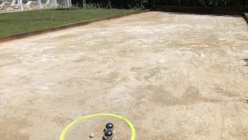 Ein Sandplatz mit gelber Begrenzung und drei Bällen darin.