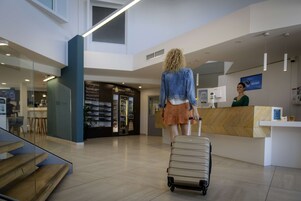 Un moderno vestíbulo de hotel con una recepción, una escalera y un panel de vidrio.
