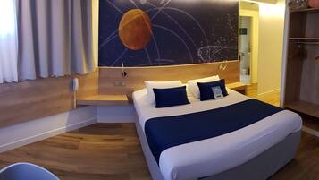 Habitación de hotel con cama, mesita de noche, teléfono en la pared y ventana con cortinas.