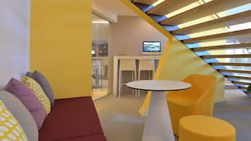 A modern interior with a yellow and white color scheme, featuring a sofa, a round table, and a TV in the background.