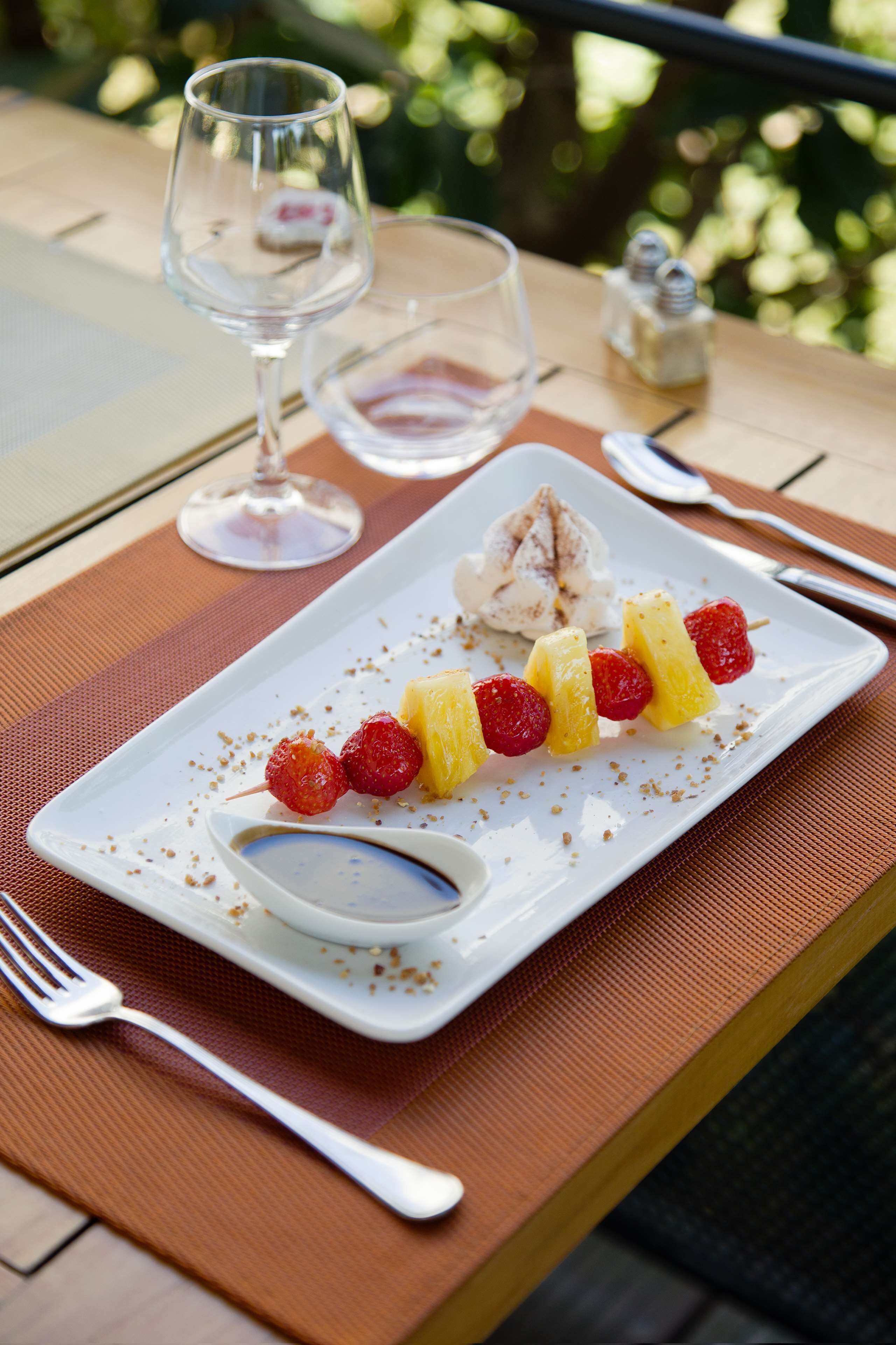 A dining table with a white plate of food, a fork, and a wine glass.