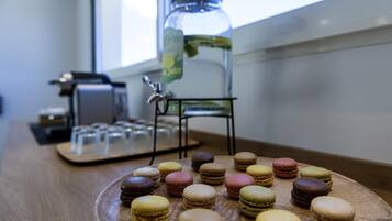 Ein Holztisch mit verschiedenen Macarons und einem Glasgefäß mit einer Grünpflanze.