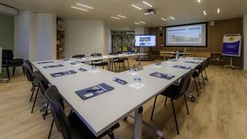 A conference room with a long table, chairs, a projector screen, and presentation materials.