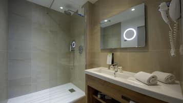 A modern bathroom with a glass-enclosed shower, a vanity with a mirror, and a hairdryer mounted on the wall.