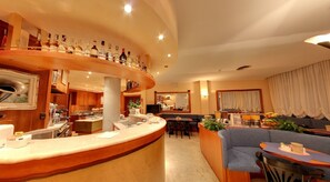 A hotel lobby with a curved bar, seating area, and a television. - Hotel Rosa (Abano Terme)