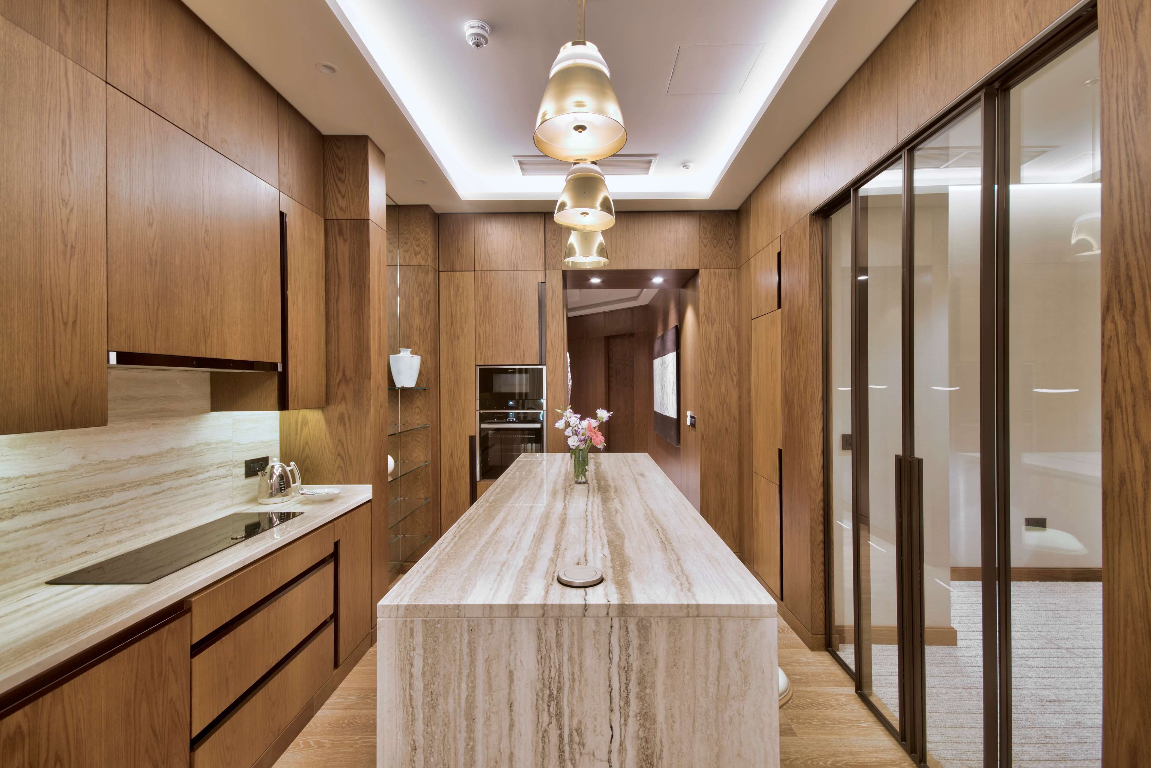 Una cucina moderna con mobili in legno, un piano di lavoro in marmo e un'isola centrale.