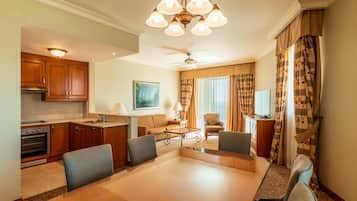 Een hotelkamer met een eethoek, kitchenette en een groot raam met gordijnen.