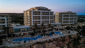 Un hotel de varios pisos, piscina y paisaje rocoso.