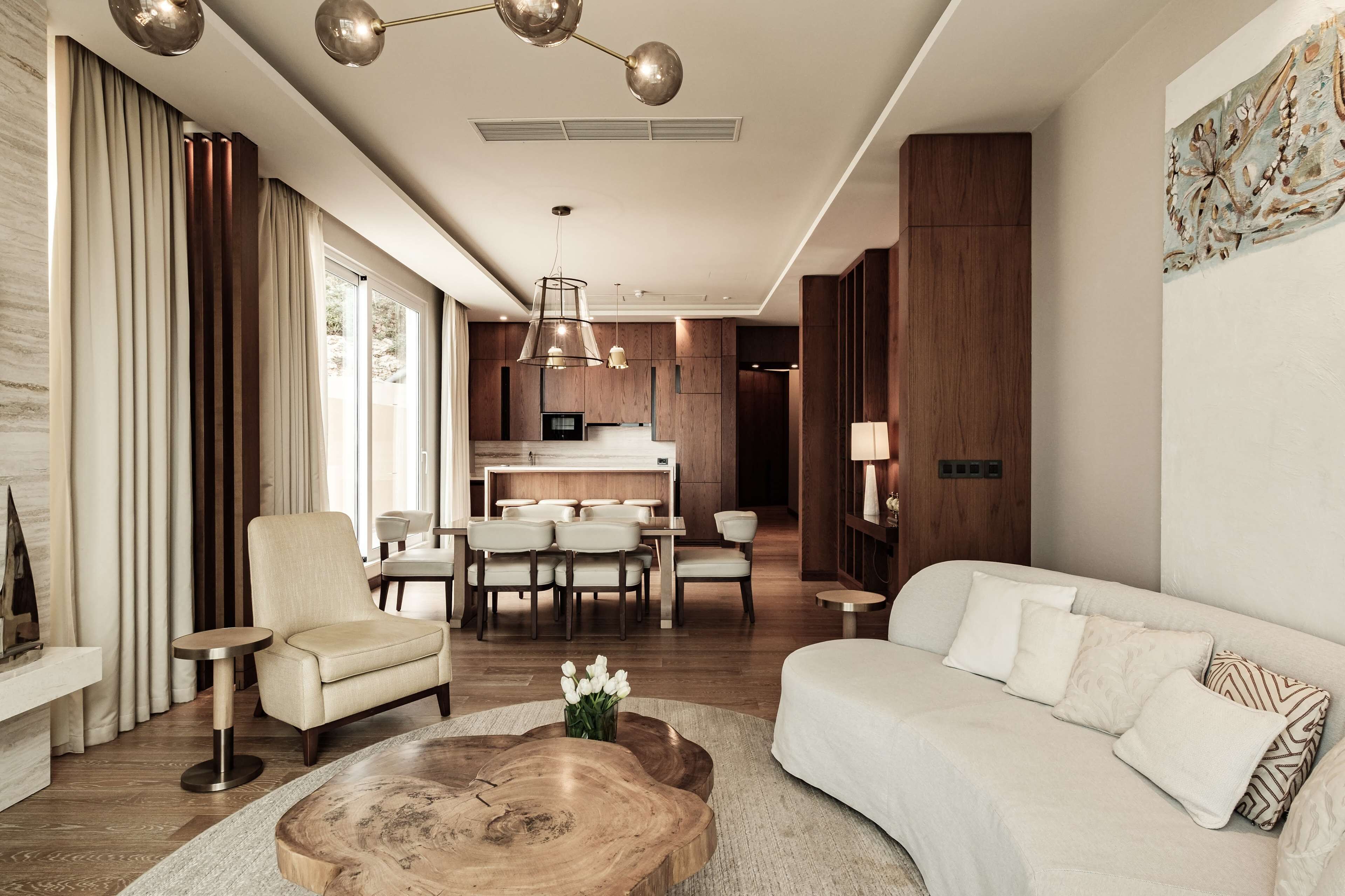A modern living room with a sofa, armchair, coffee table, and a dining area with chairs and a table.