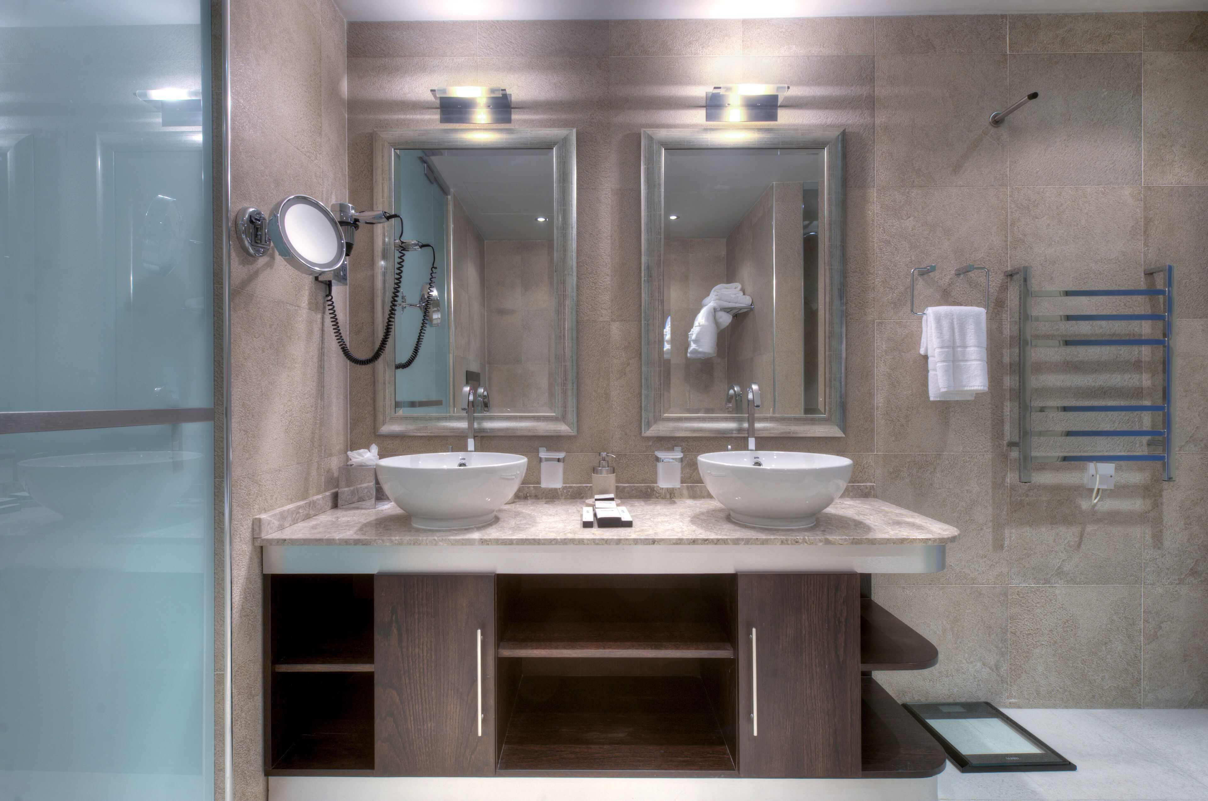 Un bagno moderno con due lavabi, cabina doccia in vetro e porta asciugamani.