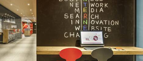 A workspace with a laptop on a desk, two chairs, and a blackboard with words related to social media and business.