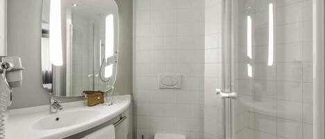 Un baño moderno con lavamanos, espejo, inodoro y ducha.