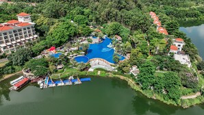 Luchtbeeld van een resort met meerdere zwembaden, een waterpark en weelderige begroeiing.