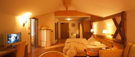Ein gemütliches Hotelzimmer mit Bett, Schreibtisch, Sessel und Fernseher.