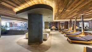 A modern spa area with wooden ceiling, lounge chairs, and a large pillar.
