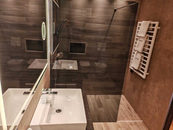 A modern bathroom with a glass-enclosed shower, a vanity with a sink, and a towel rack.