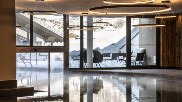 A modern interior with a reflective floor, large windows, and a view of a snowy outdoor area.
