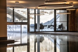 A modern interior with a reflective floor, large windows, and a view of a snowy outdoor area.